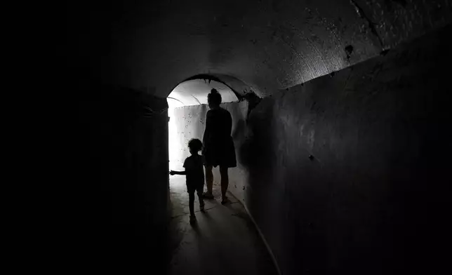 A woman and child walk through a replica of a tunnel used by Hamas militants in the Gaza Strip, ahead of a weekly protest by families of hostages held by the group to demand their release, in Tel Aviv, Israel, Saturday, Aug. 17, 2024. (AP Photo/Tsafrir Abayov)