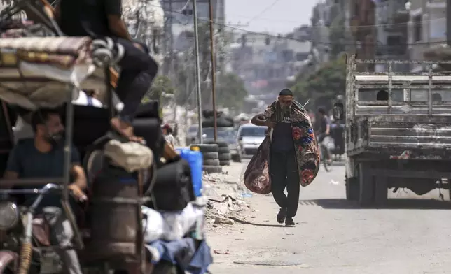 A Palestinian carries his belongings as he evacuates Maghazi refugee camp in the central Gaza Strip, as part of a mass evacuation ordered by the Israeli military ahead of an operation, Saturday, Aug. 17, 2024. (AP Photo/Abdel Kareem Hana)