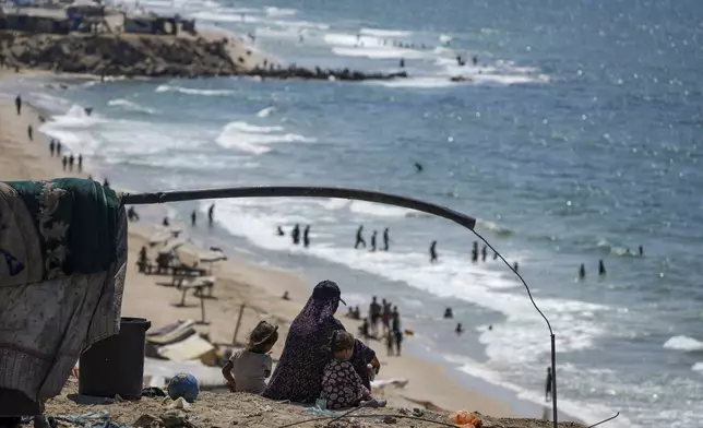 Displaced Palestinians sit next to their tent as they camp on the beach, west of Deir al-Balah, Gaza Strip, Tuesday, Aug. 20, 2024. (AP Photo/Abdel Kareem Hana)