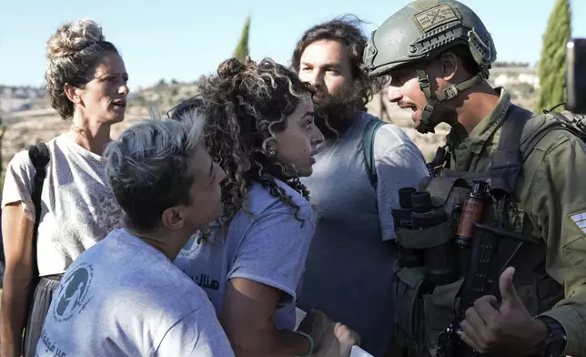 Israeli activists surround Alice Kisiya, center, as they try to enter her family's land, after the Palestinian family was forcefully evicted by Israeli settlers backed by soldiers who declared it a closed military area, in the West Bank town of Beit Jala, Friday, Aug. 2, 2024. (AP Photo/Mahmoud Illean)