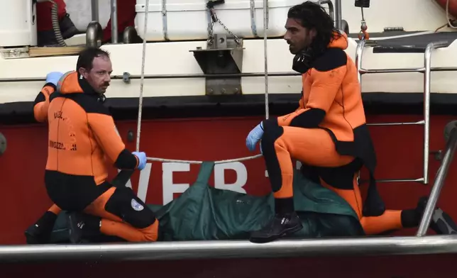 Italian firefighter scuba divers bring ashore, in the green bag, the body of one of the victims from the British-flagged vessel Bayesian, Wednesday, Aug. 21, 2024. The yacht was hit by a violent sudden storm and sank early Monday, while at anchor off the Sicilian village of Porticello near Palermo, in southern Italy. (AP Photo/Salvatore Cavalli)