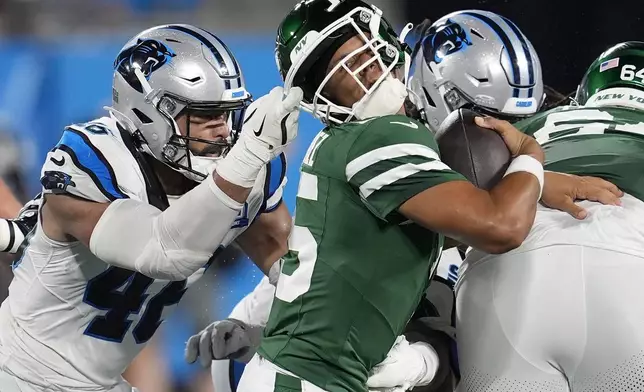 Carolina Panthers linebacker Eku Leota, left, grabs the face mask of New York Jets quarterback Adrian Martinez during the second half of a preseason NFL football game, Saturday, Aug. 17, 2024, in Charlotte, N.C. (AP Photo/Mike Stewart)