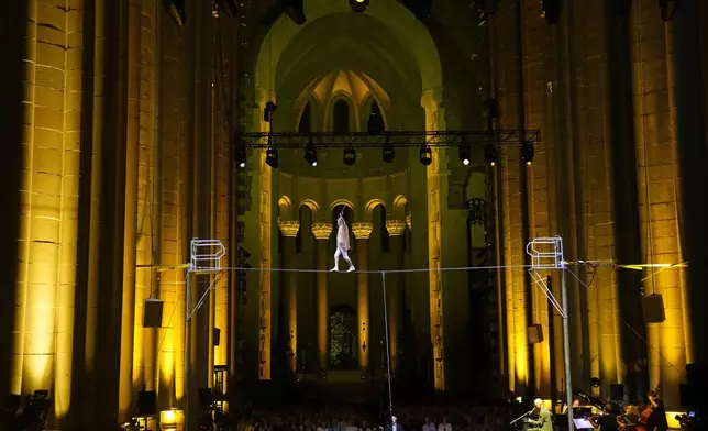 Philippe Petit walks a tightrope inside the Cathedral Church of St. John the Divine to mark the 50th anniversary of his World Trade Center Twin Towers high-wire walk, on Wednesday, Aug. 7, 2024, in New York. (Photo by Charles Sykes/Invision/AP)