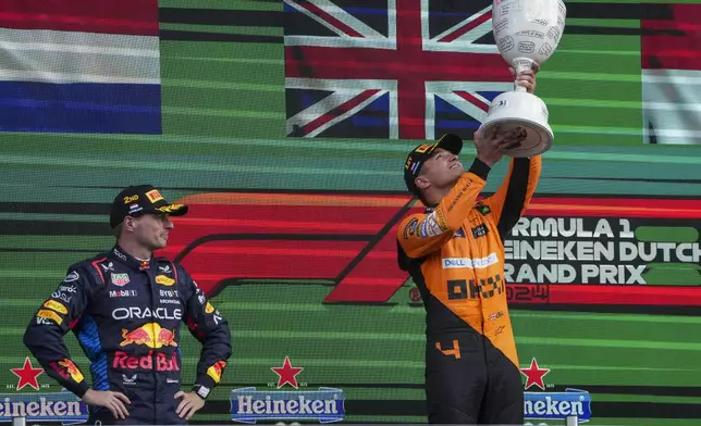 McLaren driver Lando Norris of Britain celebrates after winning the Formula One Dutch Grand Prix race, as Red Bull driver Max Verstappen of the Netherlands, left, looks on, at the Zandvoort racetrack, Netherlands, Sunday, Aug. 25, 2024. (AP Photo/Peter Dejong)