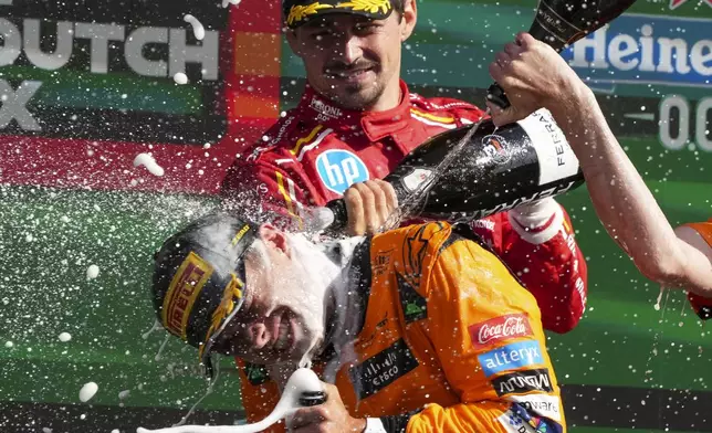 McLaren driver Lando Norris of Britain is sprayed with champagne as he celebrates after winning the Formula One Dutch Grand Prix race at the Zandvoort racetrack, Netherlands, Sunday, Aug. 25, 2024. (AP Photo/Peter Dejong)