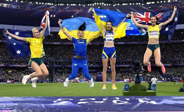 Gold medalist Yaroslava Mahuchikh, second from right, of Ukraine, jumps with silver medalist Nicola Olyslagers, right, of Australia, and bronze medal winners Iryna Gerashchenko, second from left, of Ukraine, and Eleanor Patterson, left, of Australia, following the women's high jump final at the 2024 Summer Olympics, Sunday, Aug. 4, 2024, in Saint-Denis, France. (AP Photo/Matthias Schrader)