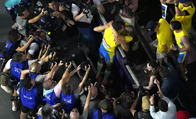 Armand Duplantis, of Sweden, gets a kiss after setting a new world record during the men's pole vault final at the 2024 Summer Olympics, Monday, Aug. 5, 2024, in Saint-Denis, France. (AP Photo/David J. Phillip)