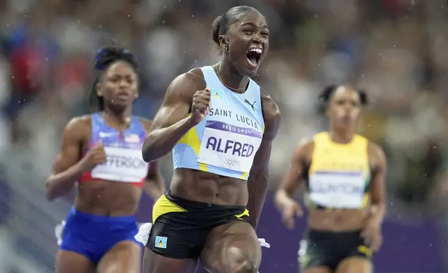 Julien Alfred, of Saint Lucia, celebrates after winning the gold medal in the women's 100 meters final at the 2024 Summer Olympics, Saturday, Aug. 3, 2024, in Saint-Denis, France. (AP Photo/Ashley Landis)