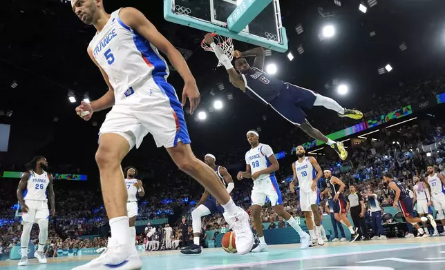 United States' LeBron James, right dunks as France's Nicolas Batum walks away during a men's gold medal basketball game at Bercy Arena at the 2024 Summer Olympics, Saturday, Aug. 10, 2024, in Paris, France. (AP Photo/Mark J. Terrill)