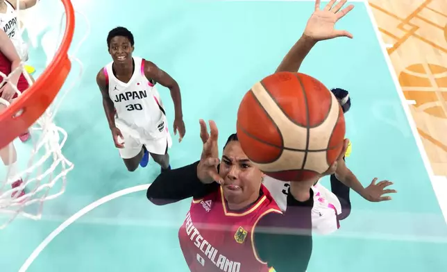 Germany's Satou Sabally, center, shoots as Japan's Stephanie Mawuli, right, defends and Japan's Evelyn Mawuli watches in a women's basketball game at the 2024 Summer Olympics, Thursday, Aug. 1, 2024, in Villeneuve-d'Ascq, France. (AP Photo/Michael Conroy, Pool)