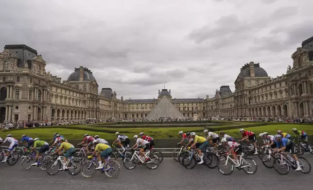 The pack of riders passes by the Louvre museum, during a men's road cycling event, at the 2024 Summer Olympics, Saturday, Aug. 3, 2024, in Paris, France. (AP Photo/Thibault Camus)