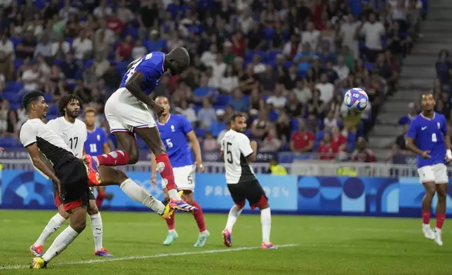 France's Jean-Philippe Mateta, top, heads the ball to score his side's 2nd goal in extra time during the men's semifinal soccer match between France and Egypt, at Lyon Stadium, during the 2024 Summer Olympics, Monday, Aug. 5, 2024, in Decines, France. (AP Photo/Silvia Izquierdo)