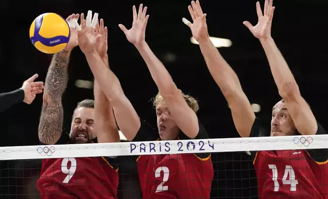 Left Gyoergy Grozer, Anton Brehme, and Moritz Karlitzek, of Germany block the ball during the Group C men's volleyball match between Argentina and Germany at the 2024 Summer Olympics, Friday, Aug. 2, 2024, in Paris, France. (AP Photo/Dolores Ochoa)