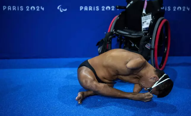 Athlete Kaewsri Charkorn, of Thailand, puts on his goggles with his foot, before swimming at a training session ahead of the 2024 Paralympics, Tuesday, Aug. 27, 2024, in Paris, France. (AP Photo/Emilio Morenatti)