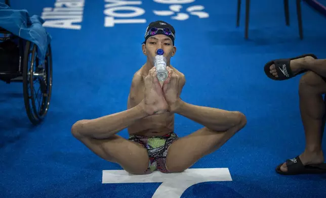 Eigo Tanaka, 20, from Japan, uses his feet to drink water from a bottle during a warmup session ahead of the 2024 Paralympics, Tuesday, Aug. 27, 2024, in Paris, France. (AP Photo/Emilio Morenatti)