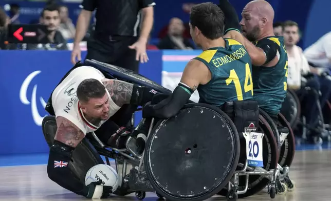 Stuart Robinson of Great Britain, left, as he is blocked by Australians Andrew Edmondson, center, and Ryley Batt during the 2024 Paralympics Wheelchair Rugby match Australia against Great Britain at the Champs Mars Arena Thursday, Aug. 29, 2024, in Paris, France. (AP Photo/Michel Euler)