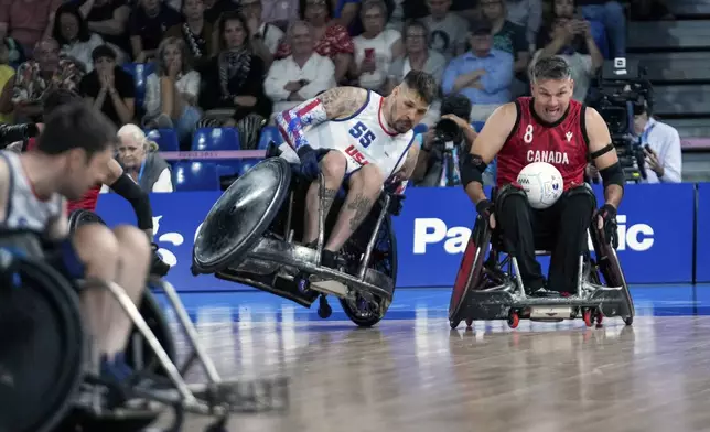 Mason Symons of the United States and Mike Whitehead of Canada, right, challenge for the ball during the 2024 Paralympics Wheelchair Rugby match United States against Canada at the Champs Mars Arena Thursday, Aug. 29, 2024, in Paris, France. (AP Photo/Michel Euler)