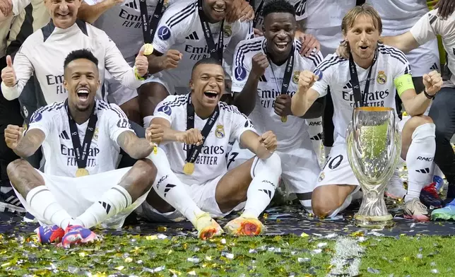 Real Madrid's Eder Militao, Kylian Mbappe, Vinicius Junior, and Luka Modric pose with the trophy after winning the UEFA Super Cup Final soccer match between Real Madrid and Atalanta at the Narodowy stadium in Warsaw, Poland, Wednesday, Aug. 14, 2024. Real Madrid won 2-0. (AP Photo/Darko Bandic)