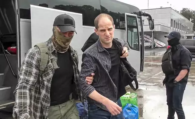 In this image made from video provided by Russian Federal Security Service via RTR on Thursday, Aug. 1, 2024, Wall Street Journal reporter Evan Gershkovich, center,is escorted by a Russian Federal Security Service agent, left, as they arrive at an airport outside Moscow, Russia. (Russian Federal Security Service/RTR via AP)