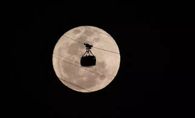 A cable car heads toward Sugarloaf Mountain as the supermoon rises into the night sky in Rio de Janeiro, Monday, Aug 19, 2024. (AP Photo/Bruna Prado)