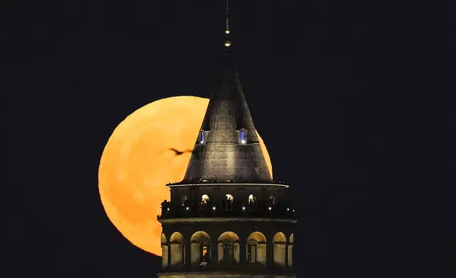 A supermoon rises behind the Galata Tower in Istanbul, Turkey, Monday, Aug. 19, 2024. (AP Photo/Khalil Hamra)