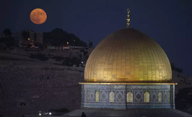 The super moon rises behind the Dome of the Rock shrine at the Al Aqsa Mosque compound in the Old City of Jerusalem, Monday, Aug. 19, 2024. (AP Photo/Leo Correa)