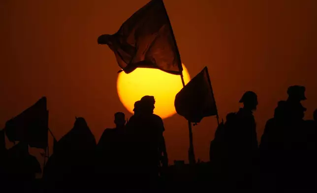 The sun sets as Shiite pilgrims march on their way to Karbala for Arbaeen in Babil, Iraq, Monday, Aug. 19, 2024. (AP Photo/Hadi Mizban)