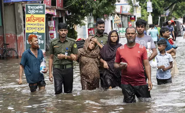 People carry their belongings and wade through flooded water to reach a temporary shelter in Feni, a coastal district in southeast Bangladesh, Friday, Aug. 23, 2024. (AP Photo/Fatima Tuj Johora)