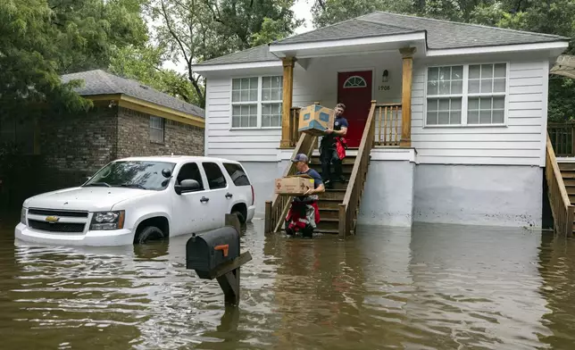 Savannah Fire Advanced Firefighters Ron Strauss, top, and Andrew Stevenson, below, carry food to residents in the Tremont Park neighborhood that where stranded in stormwater from Tropical Storm Debby, Tuesday, Aug. 6, 2024, in Savannah, Ga. (AP Photo/Stephen B. Morton)