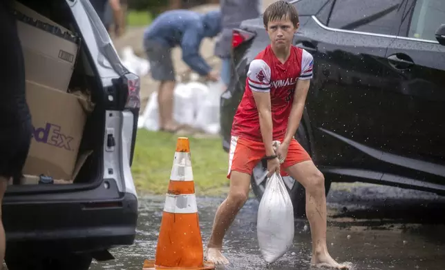 Brantley Schnabel helps his family carry sandbags to their van while preparing for Hurricane Debby at a county park, Monday, Aug. 5, 2024, in Savannah, Ga. Debby reached the Big Bend coast of Florida early Monday, bringing with it the potential for catastrophic flooding and life-threatening storm surge. (AP Photo/Stephen B. Morton)