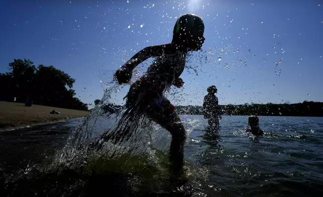 Judah Boyle, of Des Moines, Iowa, splashes water as he runs on the beach at Gray's Lake Park, Monday, Aug. 26, 2024, in Des Moines, Iowa. (AP Photo/Charlie Neibergall)