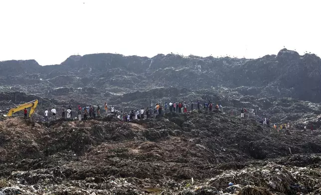 Onlookers watch as workers search for survivors at the site of a collapsed landfill in Kampala, Uganda, Sunday, Aug. 11, 2024. (AP Photo/Hajarah Nalwadda )