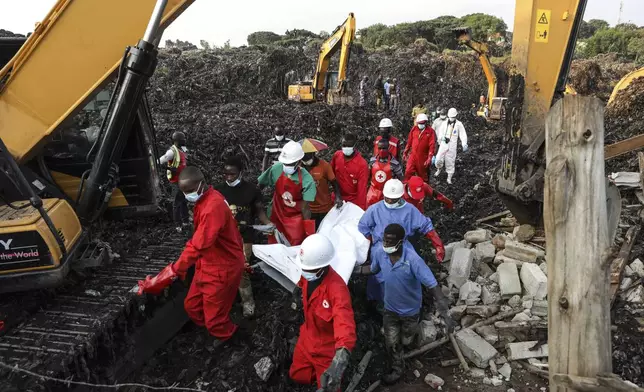 Red Cross personnel carry the body of a victim at the site of a collapsed landfill in Kampala, Uganda, Sunday, Aug. 11, 2024. (AP Photo/Hajarah Nalwadda)