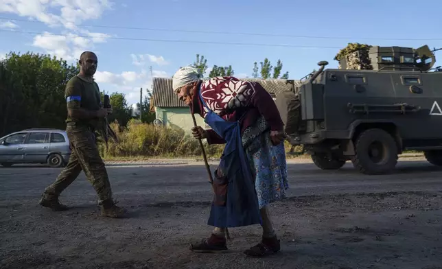 An elderly woman walks along the road near the Russian-Ukrainian border, Sumy region, Ukraine, Wednesday, Aug. 14, 2024. (AP Photo/Evgeniy Maloletka)