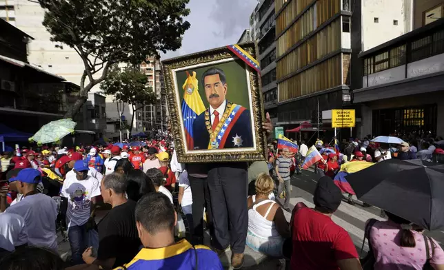 A supporter holds a framed image of President Nicolas Maduro as people gather for a government rally in Caracas, Venezuela, Saturday, Aug. 3, 2024. (AP Photo/Matias Delacroix)