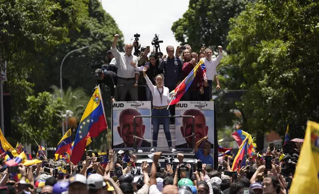 Opposition leader Maria Corina Machado holds a national flag while waving to supporters as she arrives for a rally in Caracas, Venezuela, Saturday, Aug. 3, 2024. (AP Photo/Matias Delacroix)