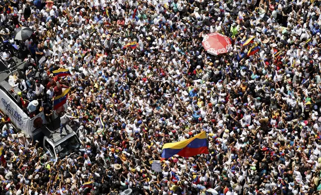 Opposition leader Maria Corina Machado, lower right, waves a Venezuelan national flag, during a rally to protest official results that declared President Nicolas Maduro the winner of the July presidential election, in Caracas, Venezuela, Saturday, Aug. 17, 2024. (AP Photo/Cristian Hernandez)