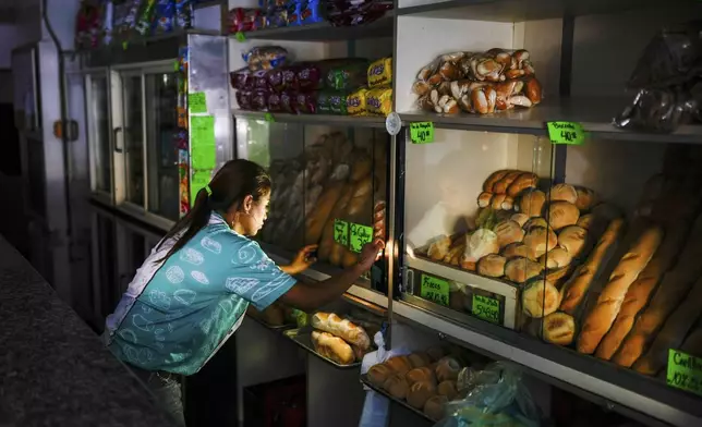 A bakery worker adjusts the shop during a blackout in Caracas, Venezuela, Friday, Aug. 30, 2024. (AP Photo/Ariana Cubillos)