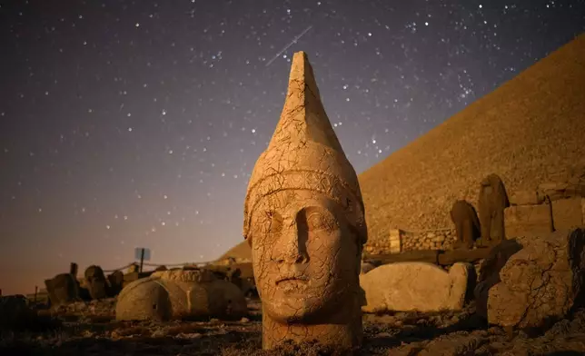 Ancient statues are seen during the Perseid meteor shower atop Mount Nemrut in southeastern Turkey, Sunday, Aug.11, 2024. (AP Photo/Emrah Gurel)