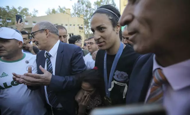 Olympic gold medalist in the the women's 66 kg boxing Algeria's Imane Khelif, center, smiles as she arrives home after returning from the 2024 Paris Olympic Games in Tiaret, Algeria, Friday, Aug. 16, 2024. (AP Photo/Anis Belghoul)