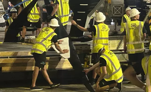 Emirates Team New Zealand inspects the team’s America’s Cup boat after it was damaged when a crane failed while moving it from the water to its cradle after the opening day of racing on Thursday Aug. 29, 2024 in Barcelona, Spain. (AP Photo/Joseph Wilson)