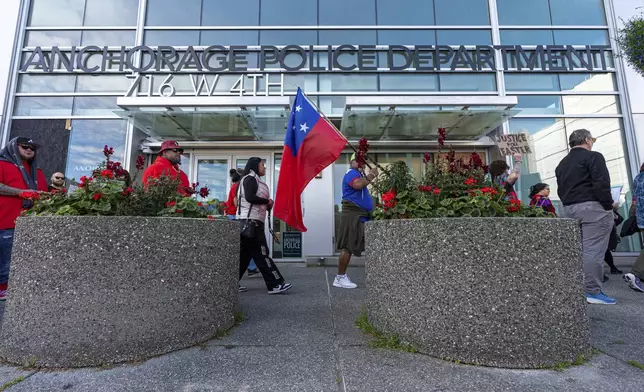 Attendees hold signs and the flag of Western Samoa during a march for Easter Leafa, a 16-year-old recently fatally shot by police, on Saturday, Aug. 17, 2024, outside the police headquarters in Anchorage, Alaska. (Loren Holmes/Anchorage Daily News via AP)