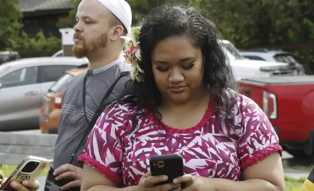 Tammalivis Salanoa with the Polynesian Association of Alaska, is shown using her phone after a prayer vigil Friday, Aug. 16, 2024, in downtown Anchorage, Alaska, after police shot and killed 16-year-old Easter Leafa, who had recently moved from American Samoa. (AP Photo/Mark Thiessen)