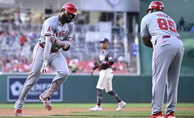 Los Angeles Angels' Jo Adell, left, is greeted by Angels third base coach Eric Young Sr., right, on his way home on a two-run home run during the second inning of a baseball game against the Washington Nationals, Friday, Aug. 9, 2024, in Washington. (AP Photo/John McDonnell)