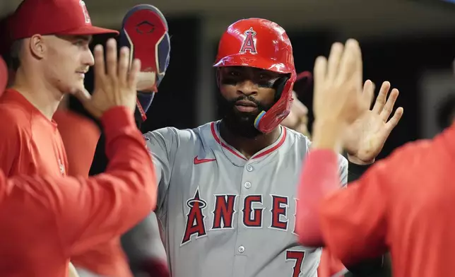 Los Angeles Angels' Jo Adell is greeted in the dugout after scoring on a sacrifice by Taylor Ward during the fifth inning of a baseball game against the Detroit Tigers, Tuesday, Aug. 27, 2024, in Detroit. (AP Photo/Carlos Osorio)