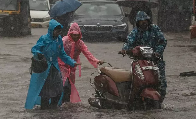 FILE - Children push their father's scooter through a flooded street as it rains in Mumbai, India, on July 25, 2024. (AP Photo/Rafiq Maqbool, File)