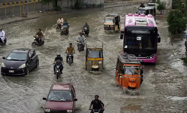 FILE - Motorcyclists and cars drive through a flooded road caused by heavy monsoon rainfall in Karachi, Pakistan, on July 30, 2024. (AP Photo/Fareed Khan, File)