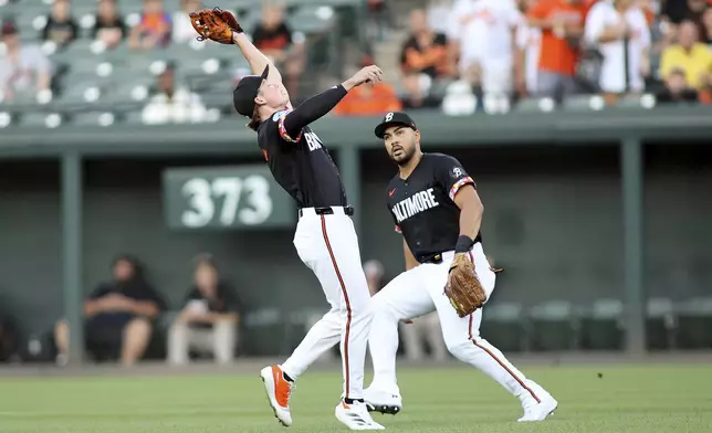 Baltimore Orioles second baseman Jackson Holliday, left, secures a popup for an out during the first inning of a baseball game against the Houston Astros, Friday, Aug. 23, 2024, in Baltimore. (AP Photo/Daniel Kucin Jr.)