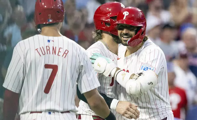 Philadelphia Phillies' Nick Castellanos, right, is cheered by Trea Turner (7) and Bryce Harper after hitting a three run homer in the third inning of a baseball game, Tuesday, Aug. 27, 2024, in Philadelphia. (AP Photo/Laurence Kesterson)