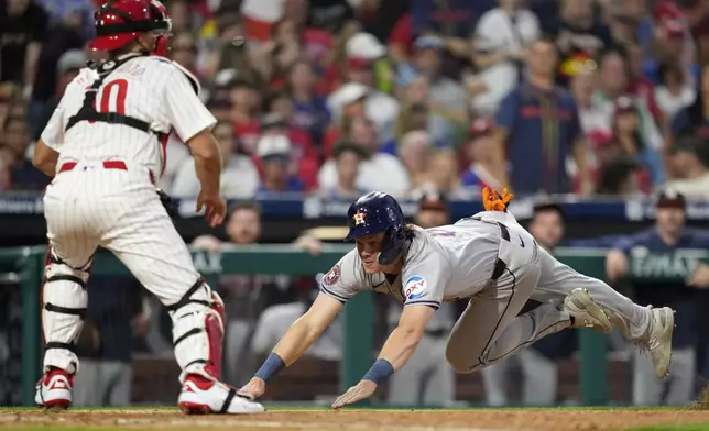 Houston Astros' Jake Meyers, right, scores against Philadelphia Phillies catcher J.T. Realmuto on a two-run double by Shay Whitcomb during the fourth inning of a baseball game, Monday, Aug. 26, 2024, in Philadelphia. (AP Photo/Matt Slocum)